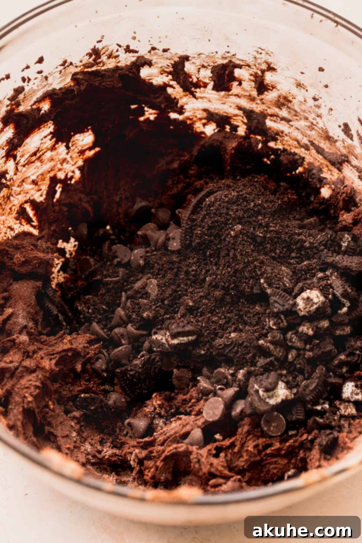 Ultimate Oreo Brookie Indulgence 8 Crushed Oreos and chocolate chips scattered over dark brownie cookie dough, ready to be mixed.