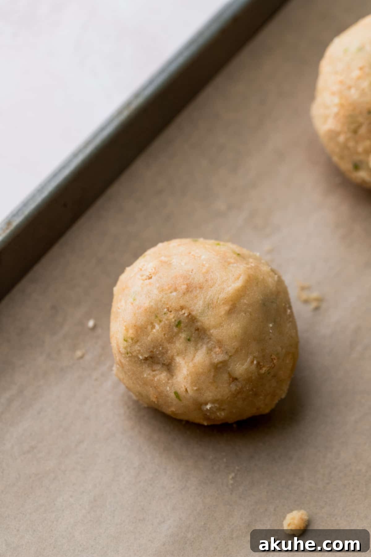 Zesty Key Lime Cookies 10 A perfectly sealed and rolled Key Lime Cookie dough ball on a baking sheet, ready for the oven.