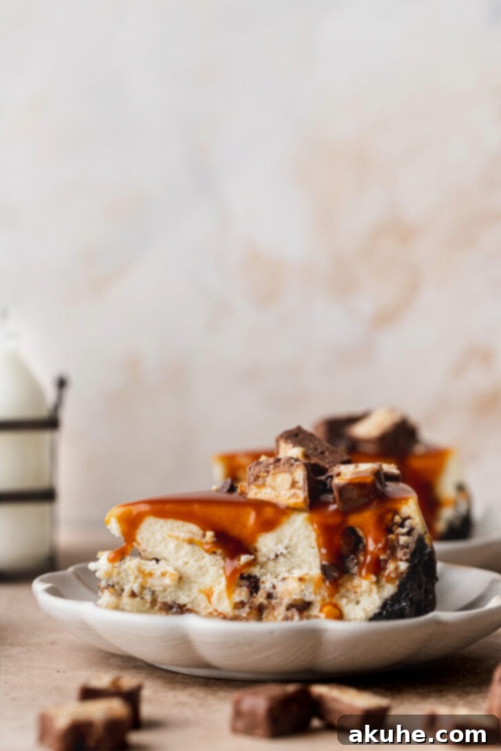 Snickers Bar Cheesecake Perfection 8 A pristine slice of Snickers cheesecake, showcasing its layered beauty, served on a white plate.