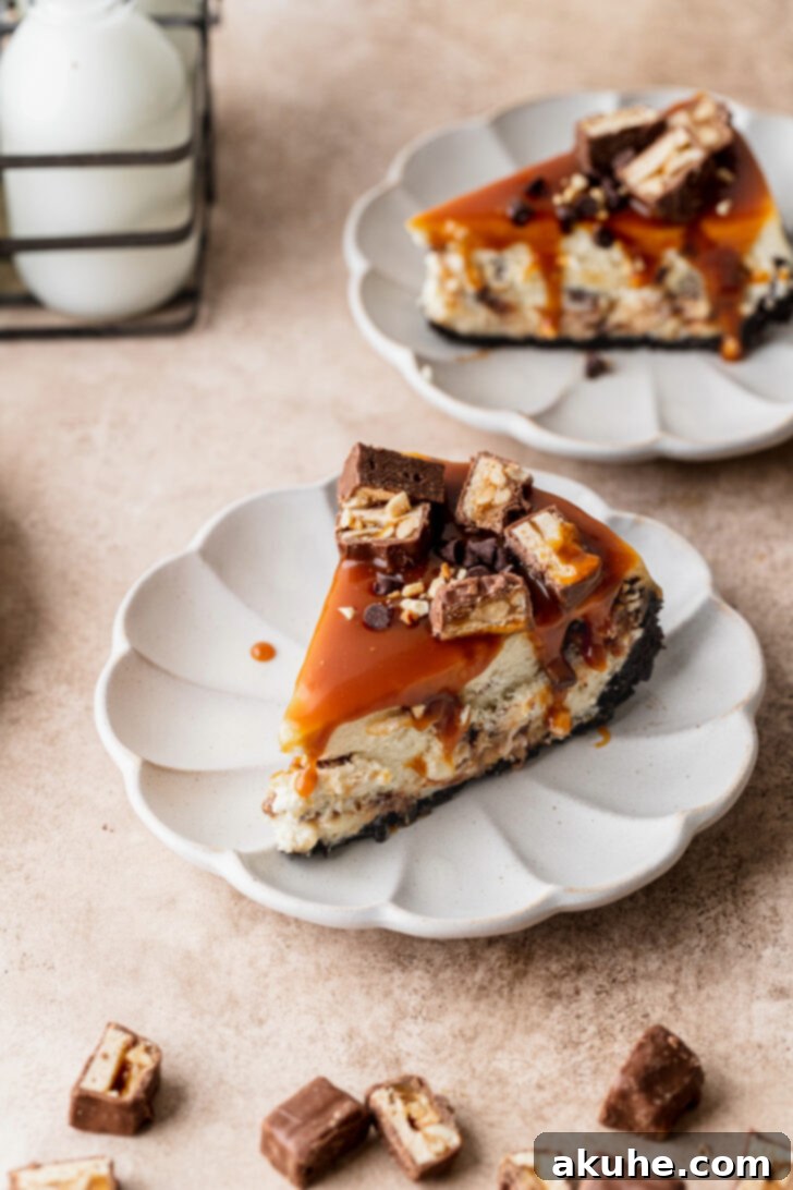 Snickers Bar Cheesecake Perfection 9 A top-down view of a single, perfectly cut slice of Snickers cheesecake on a pristine white plate, adorned with caramel and Snickers.