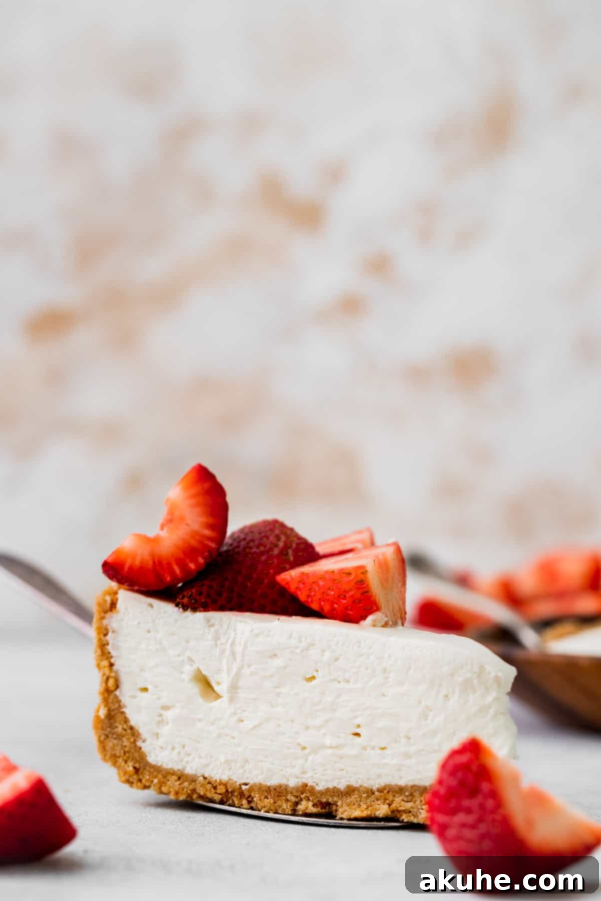 A single slice of creamy no-bake vanilla cheesecake, beautifully presented on a pie cutter, showcasing its layers of golden crust and pristine white filling.