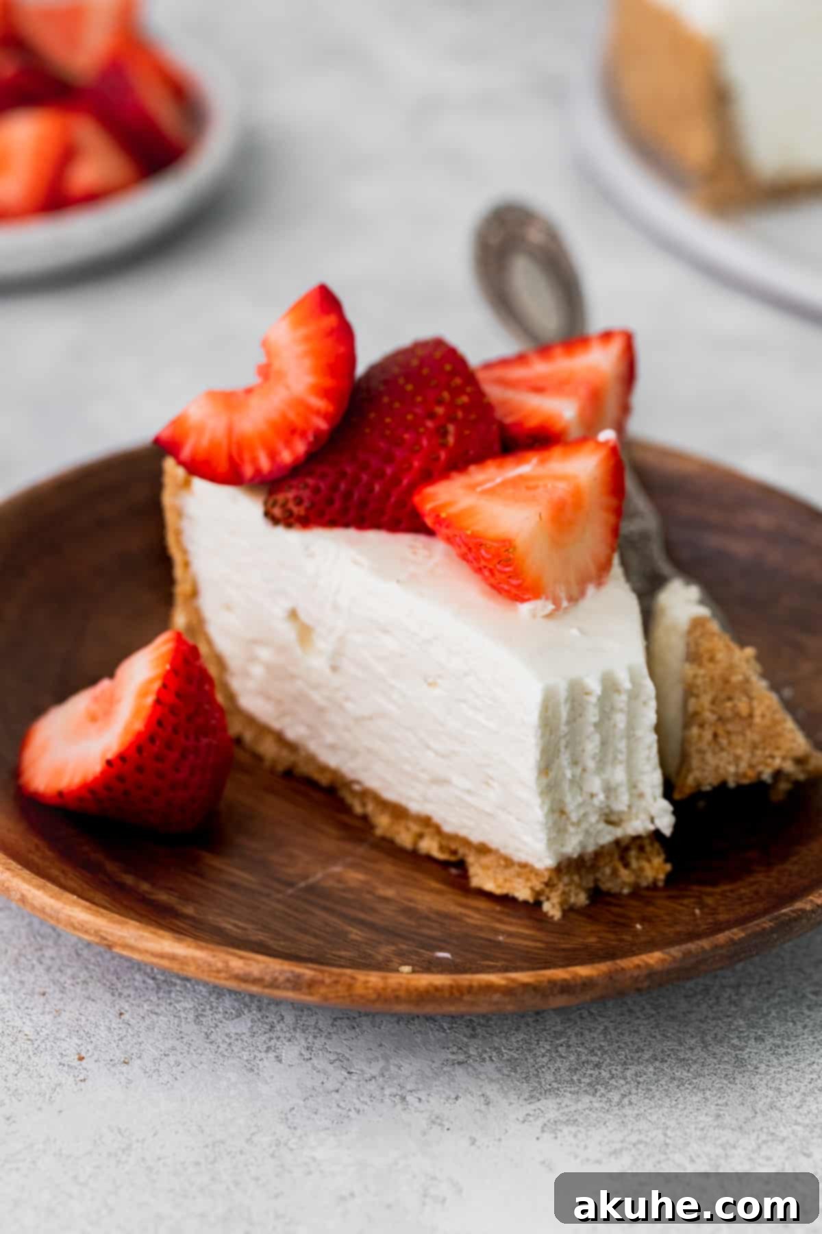 A perfectly portioned slice of no-bake vanilla cheesecake, elegantly presented on a rustic wood plate, ready to be enjoyed.