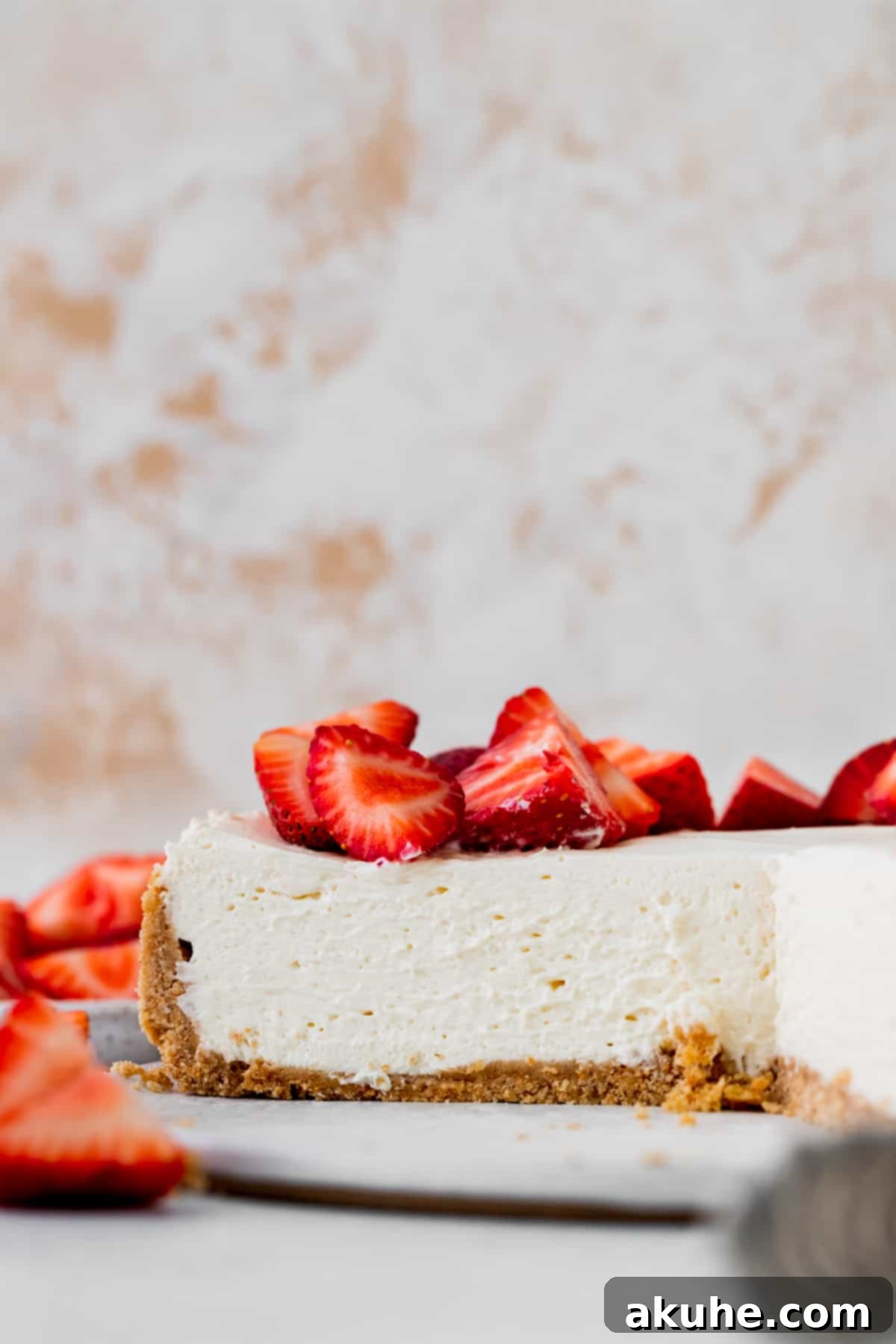 A beautiful side view of the vanilla no-bake cheesecake, highlighting its distinct layers of crumbly crust and smooth, white filling, set on a clean white board.