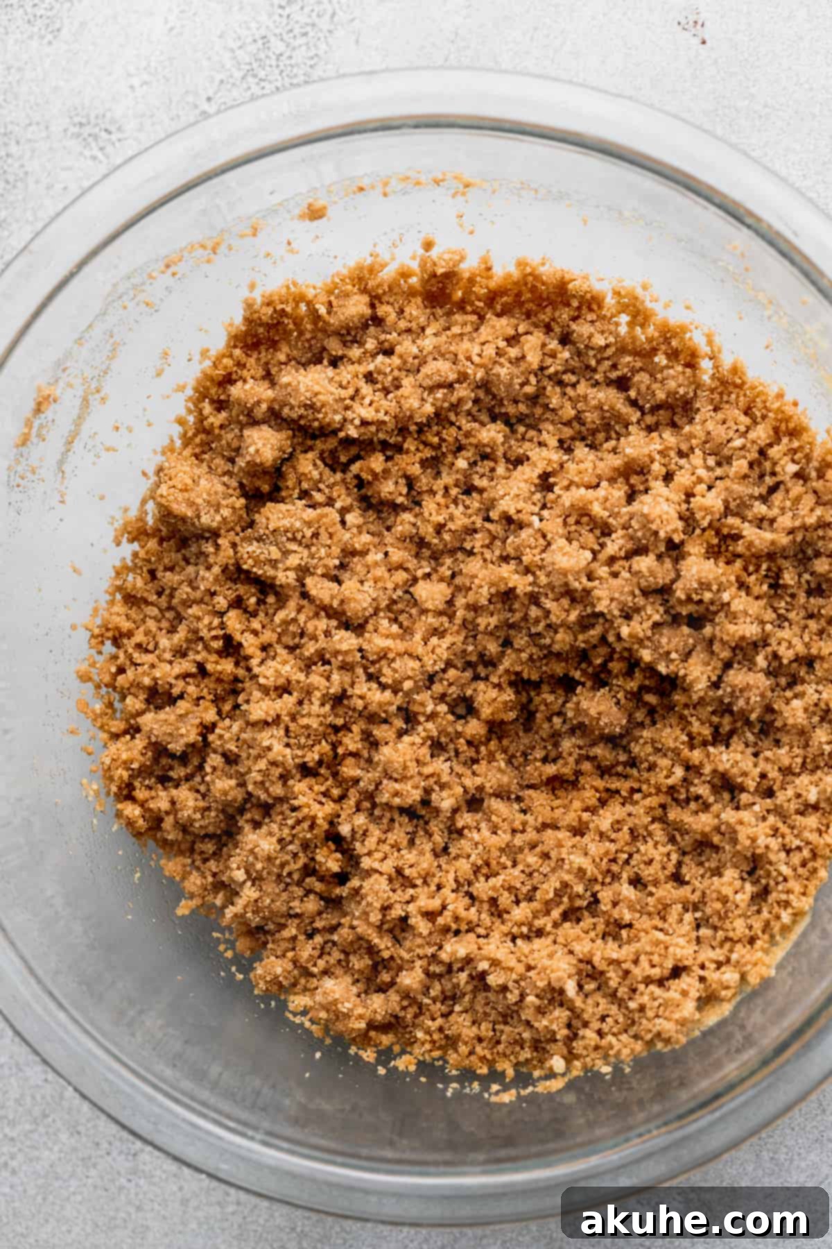 Close-up of golden graham cracker crumbs, perfectly ground and ready for mixing, showcased in a clear glass bowl.