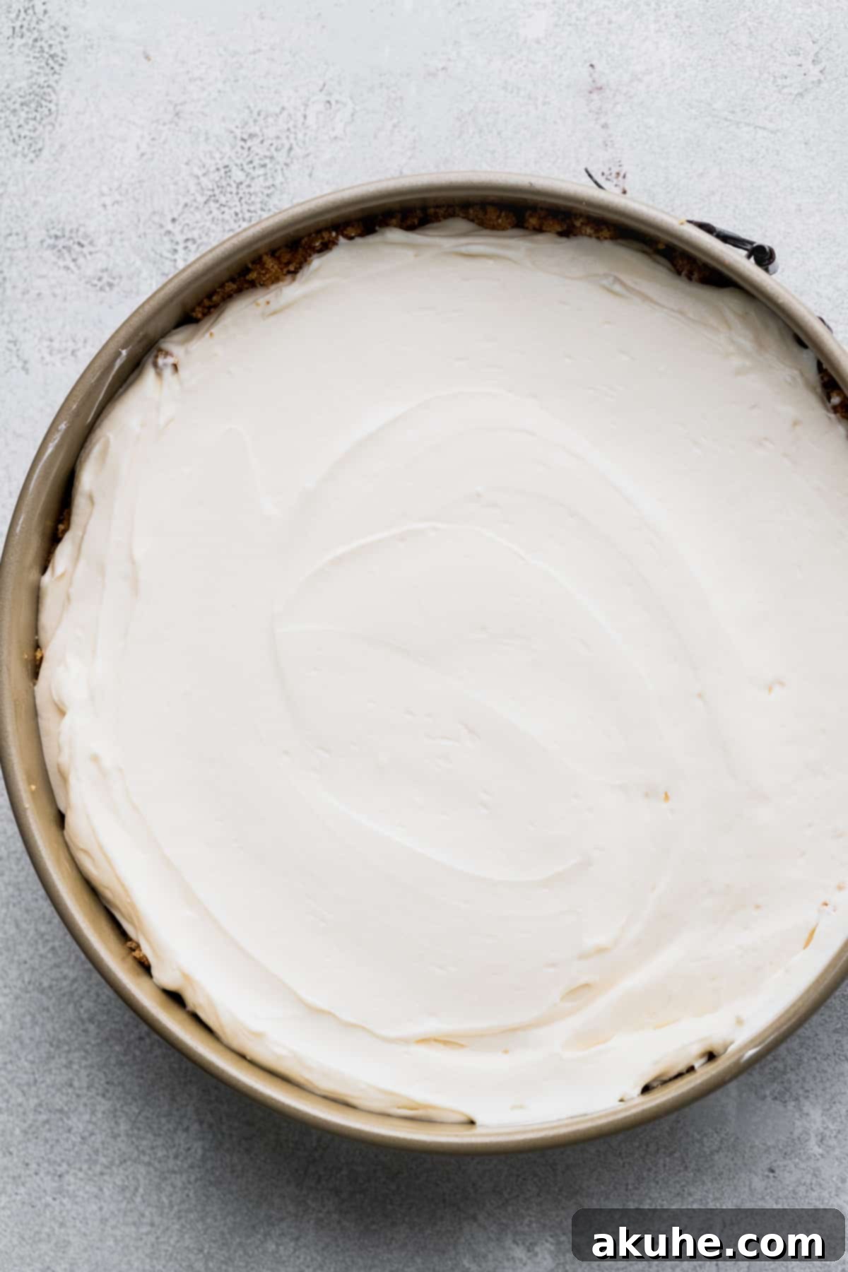 The delicate cheesecake batter, perfectly smoothed, resting in a springform pan, awaiting its essential chill time.