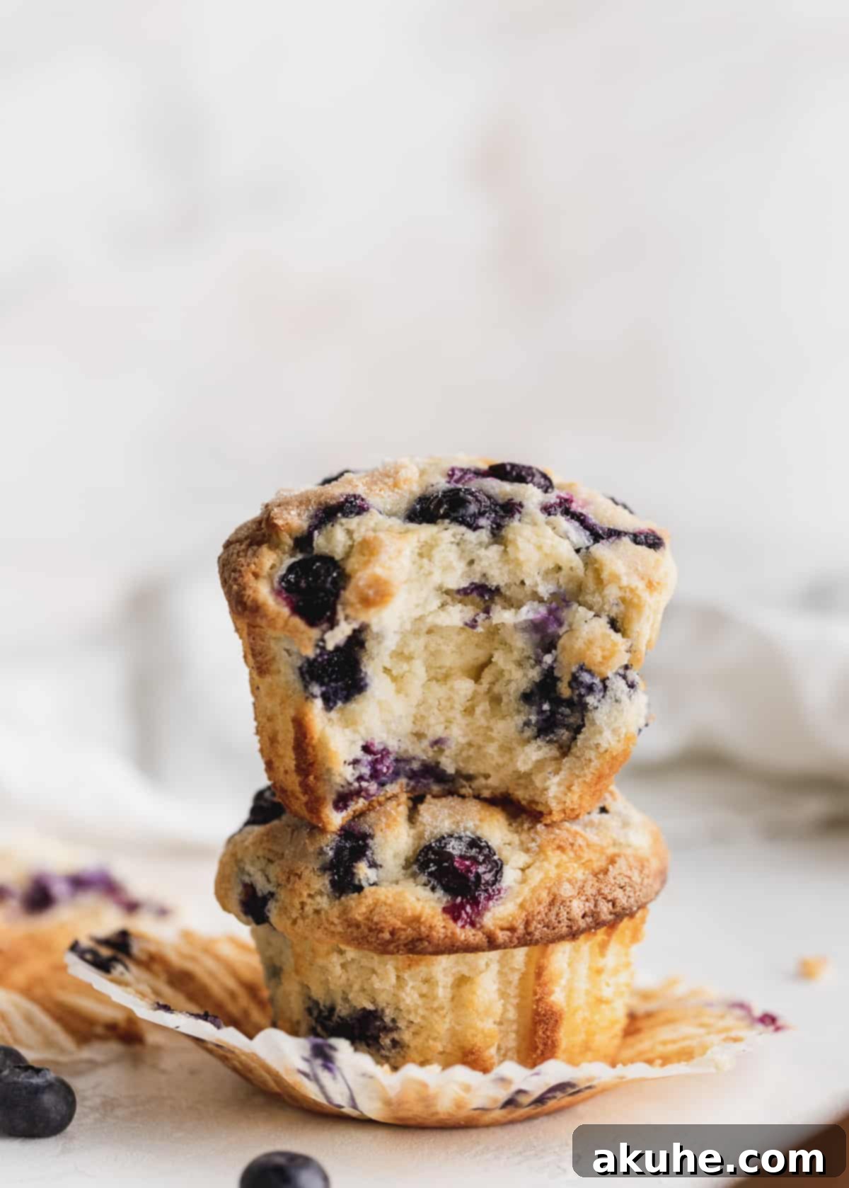 Giant Bakery Style Blueberry Muffins 3 Stacked jumbo blueberry muffins on a wrapper, showing their soft interior and crisp topping.