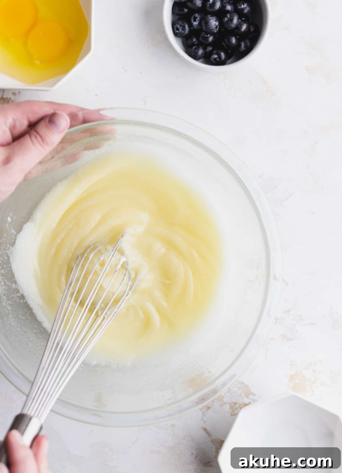 Giant Bakery Style Blueberry Muffins 4 Mixing wet batter in a clear glass bowl, showcasing the smooth texture.