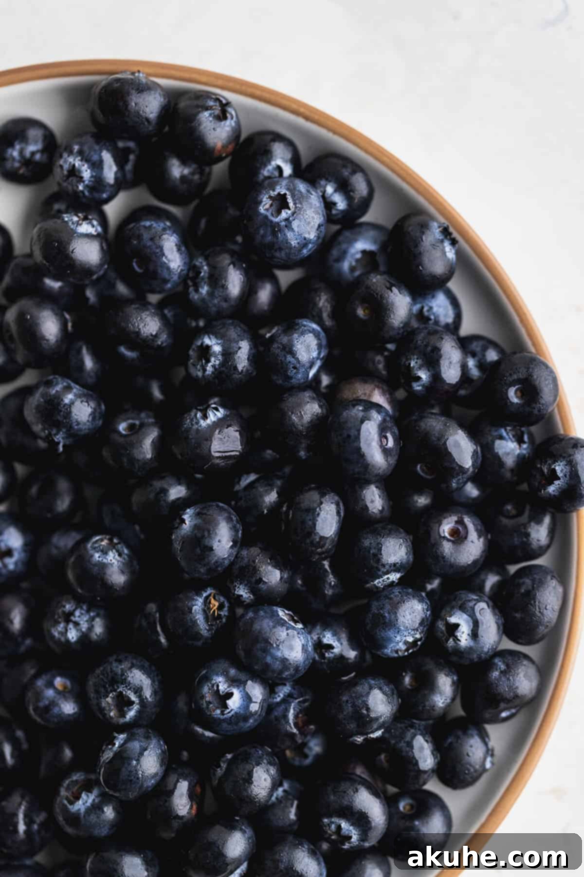 Giant Bakery Style Blueberry Muffins 6 Fresh, vibrant blueberries neatly arranged on a white plate, ready for baking.