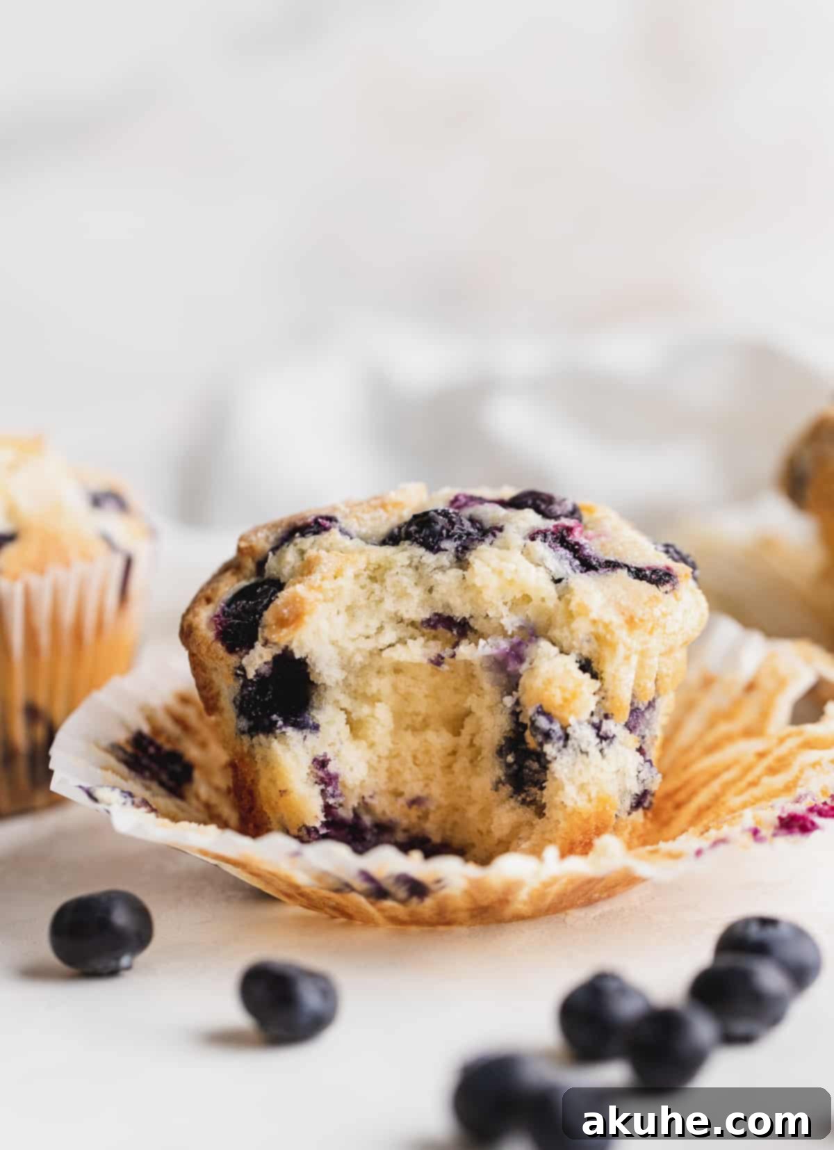 Giant Bakery Style Blueberry Muffins 8 A jumbo blueberry muffin with a bite missing, showing the tender crumb and blueberries inside.