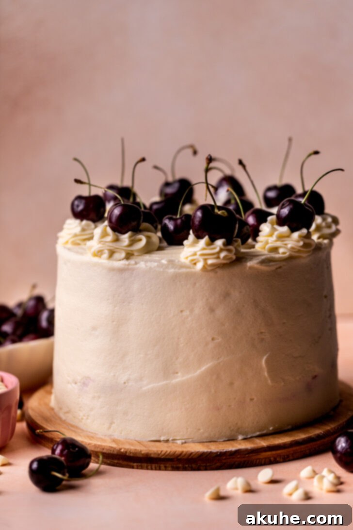 A fully decorated White Forest Cake resting on a rustic wooden board, garnished with elegant frosting dollops and fresh cherries on top, ready for serving.