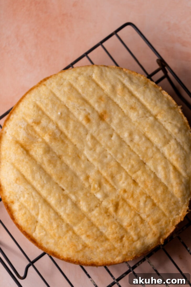 A freshly baked, golden-brown cake layer resting on a wire rack, indicating it's in the process of cooling down after being removed from the oven.