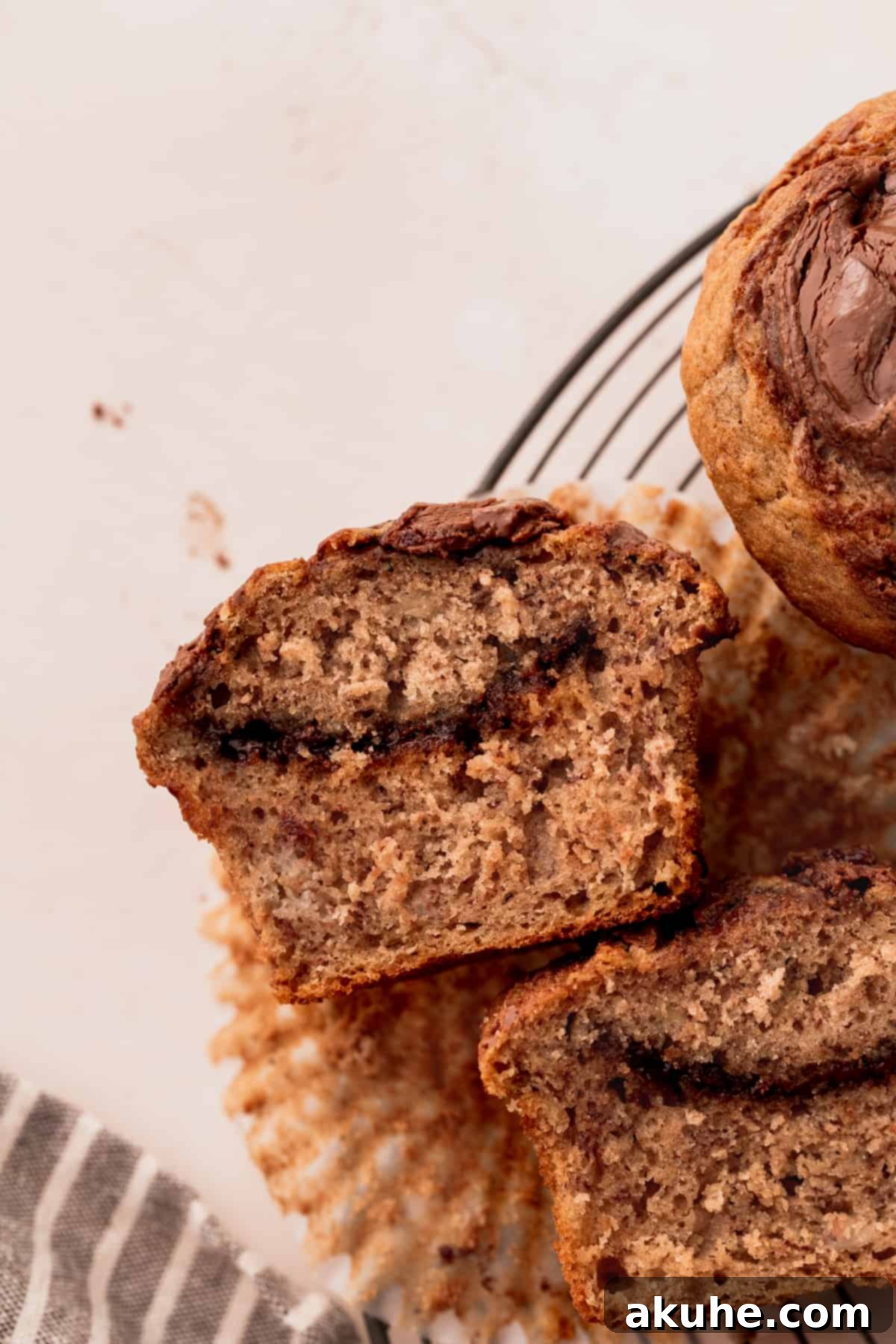 Nutella Swirl Banana Muffins 11 A Nutella banana muffin split in half, revealing its moist crumb and generous streaks of chocolate-hazelnut spread.