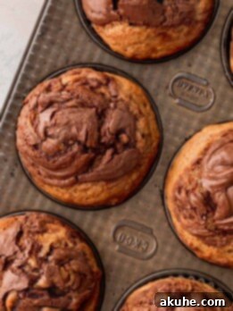Nutella Swirl Banana Muffins 12 Nutella banana muffins in a muffin pan.