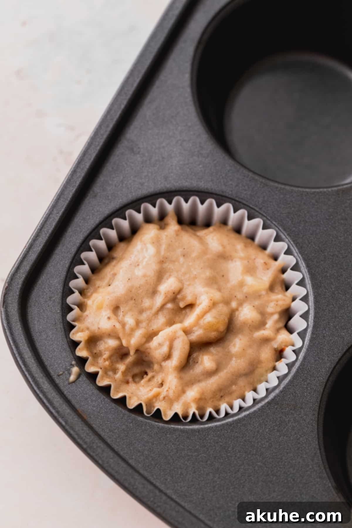 Nutella Swirl Banana Muffins 8 Muffin liners filled to the top with banana bread batter, after the initial Nutella swirl layer.