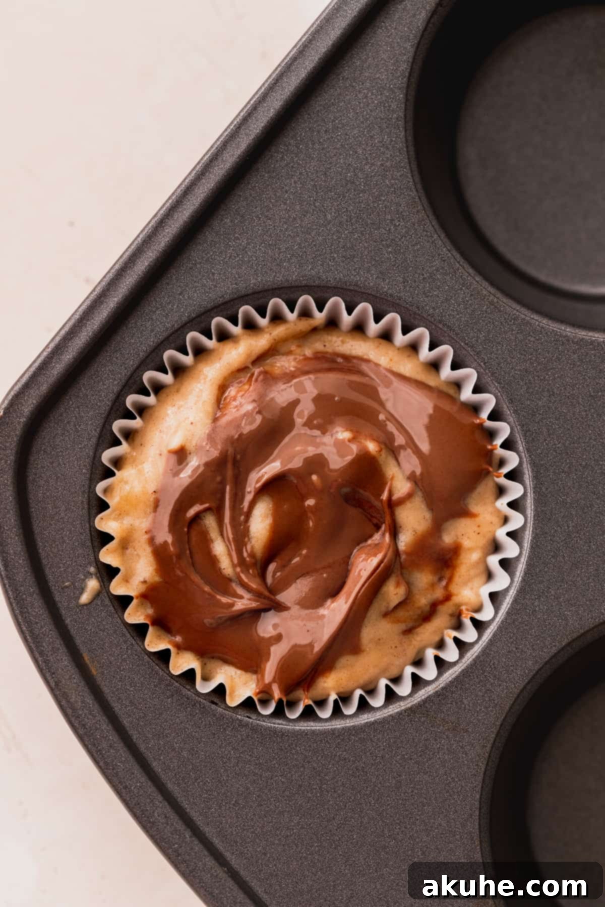 Nutella Swirl Banana Muffins 9 Close-up of muffin batter in liners, each adorned with a final swirl of Nutella on top, ready for baking.