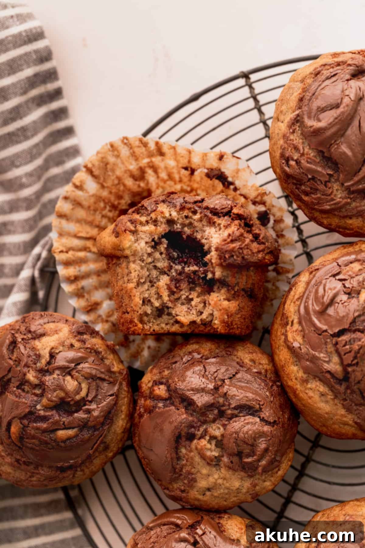 Nutella Swirl Banana Muffins 10 A delicious Nutella banana muffin on a wire rack with a bite taken out, revealing its moist interior and Nutella swirl.