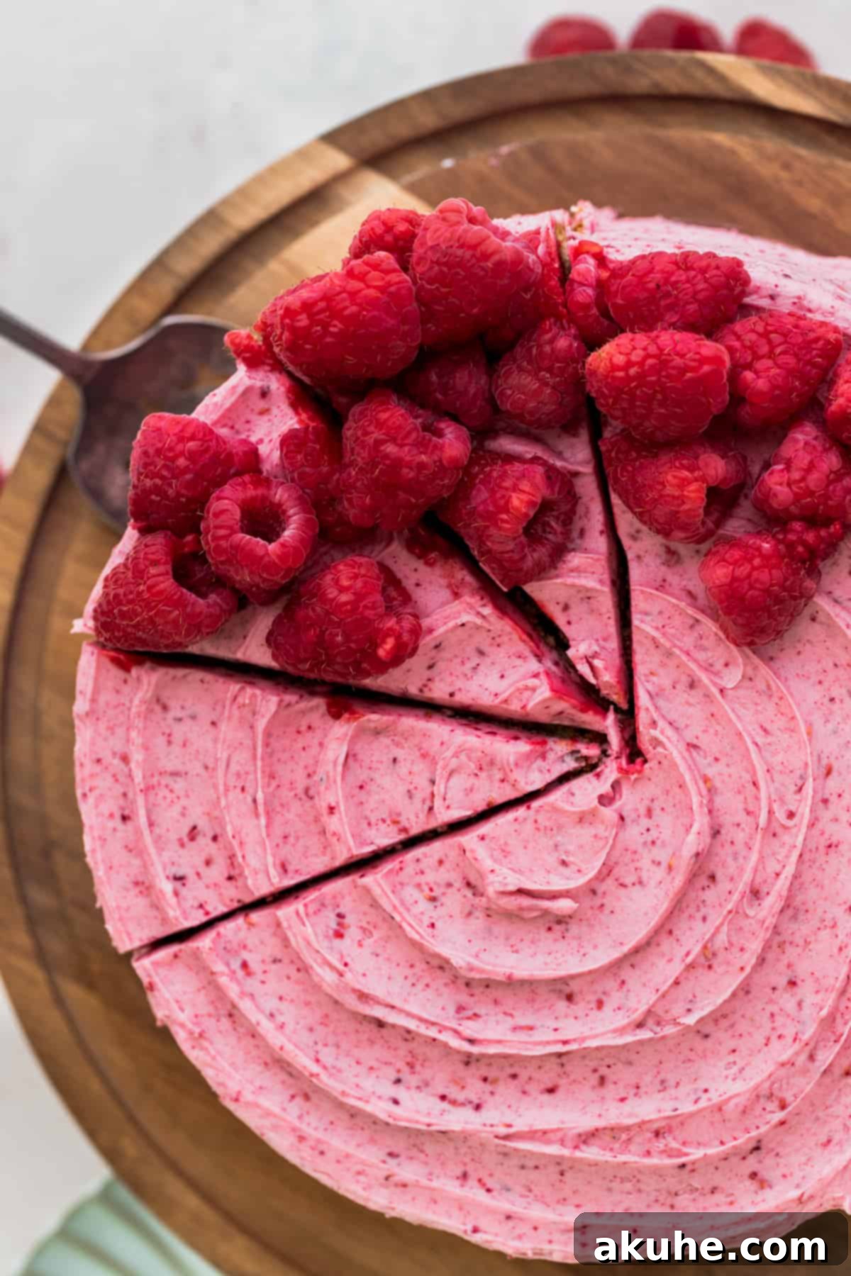 A top-down view of the beautifully frosted vanilla raspberry cake, with three slices already cut out, revealing the distinct layers within.