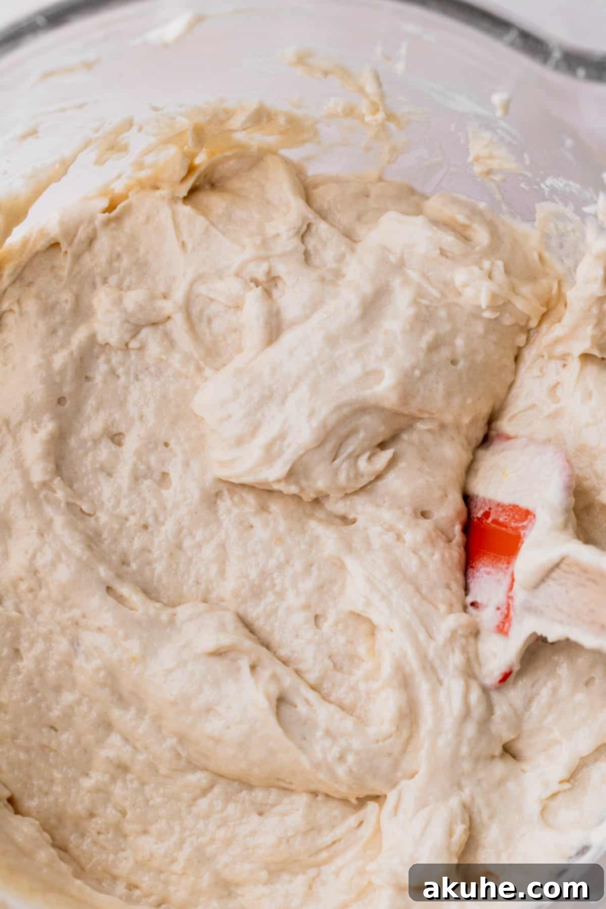 Smooth, light vanilla cake batter resting in a clear glass bowl, showcasing its consistent and airy texture before baking.