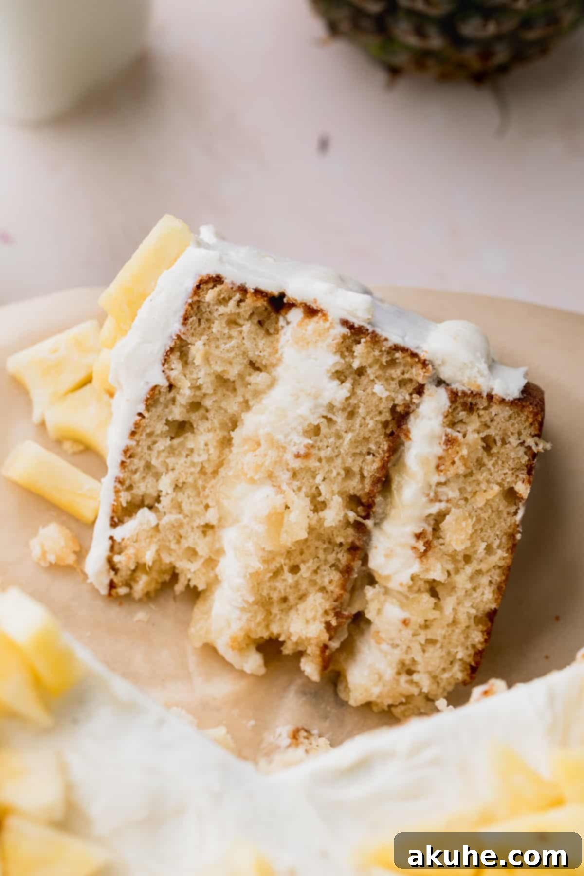 Tropical Pineapple Delight 3 A perfectly sliced piece of Pineapple Sunshine Cake on parchment paper.
