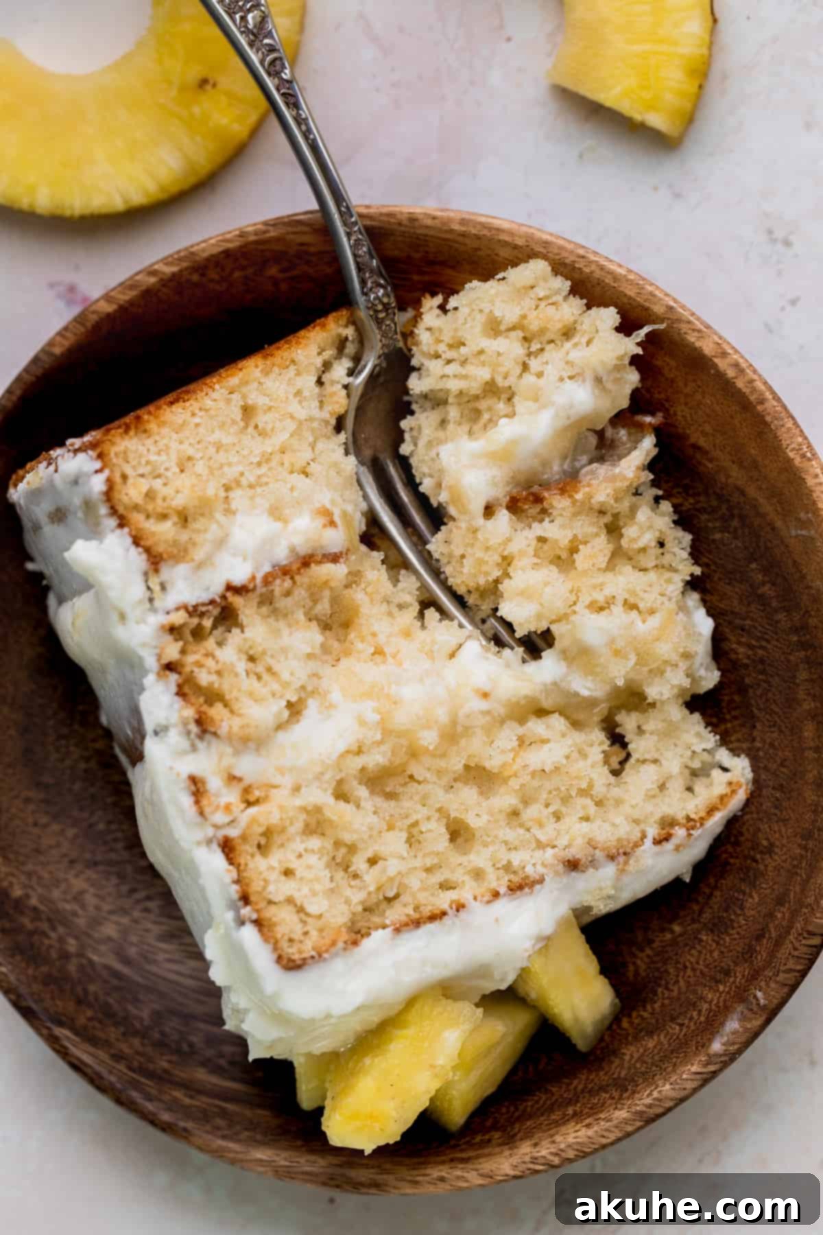 Tropical Pineapple Delight 4 A slice of homemade Pineapple Sunshine Cake on a rustic wooden plate.