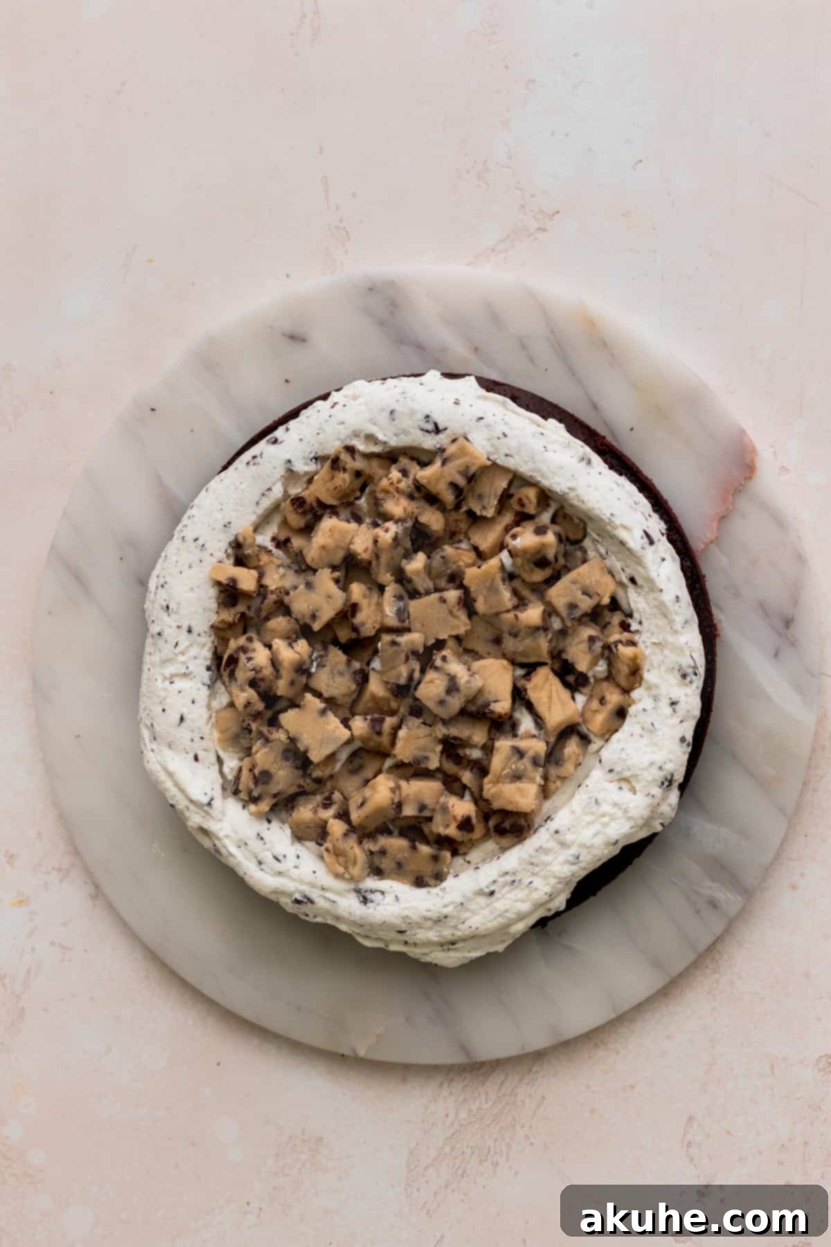 Ultimate Cookie Dough Ice Cream Cake 13 Edible cookie dough bites spread evenly over a layer of whipped cream on the cake.