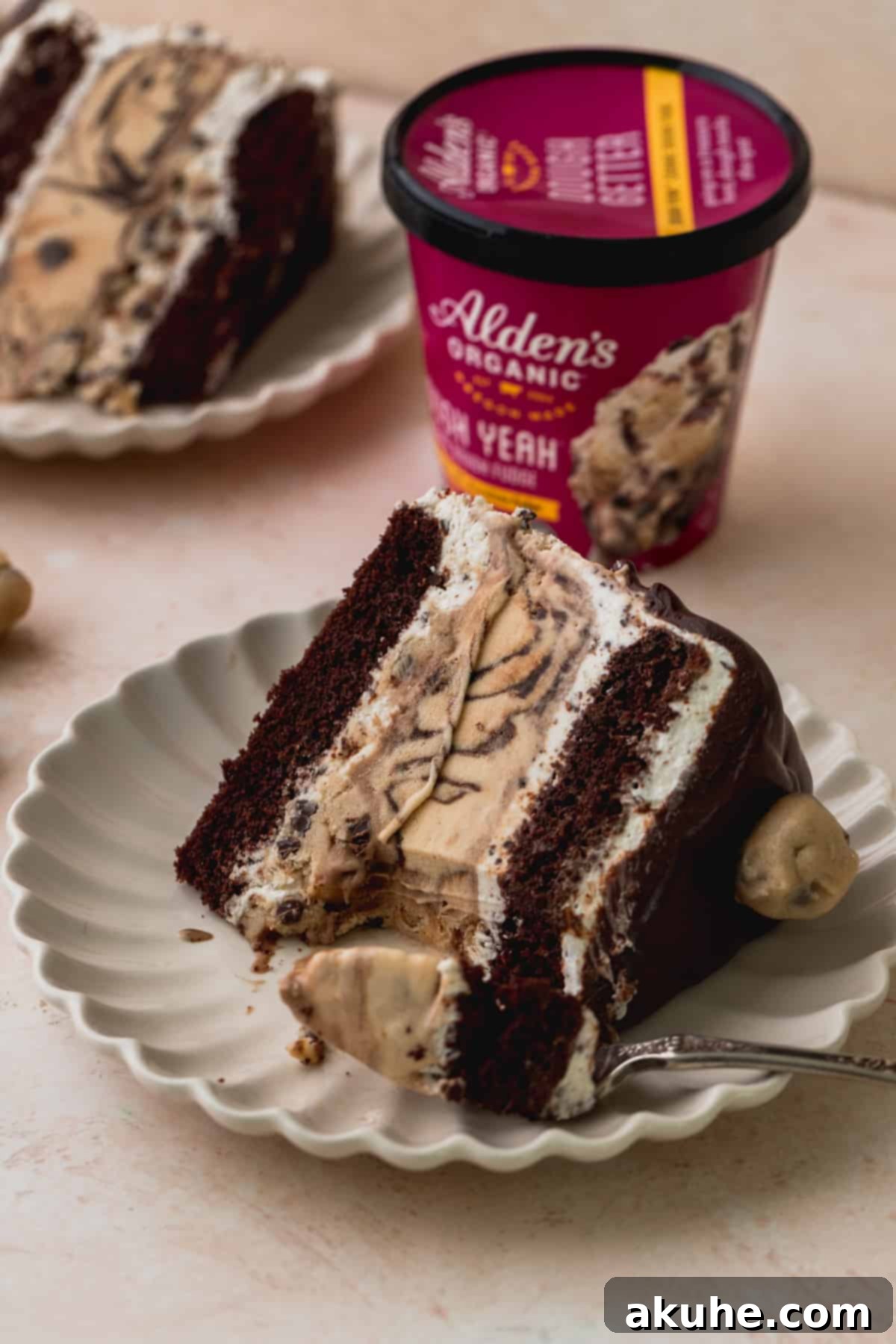 Ultimate Cookie Dough Ice Cream Cake 4 A single, delectable slice of cookie dough ice cream cake, served on a white plate with a fork, ready to be enjoyed.