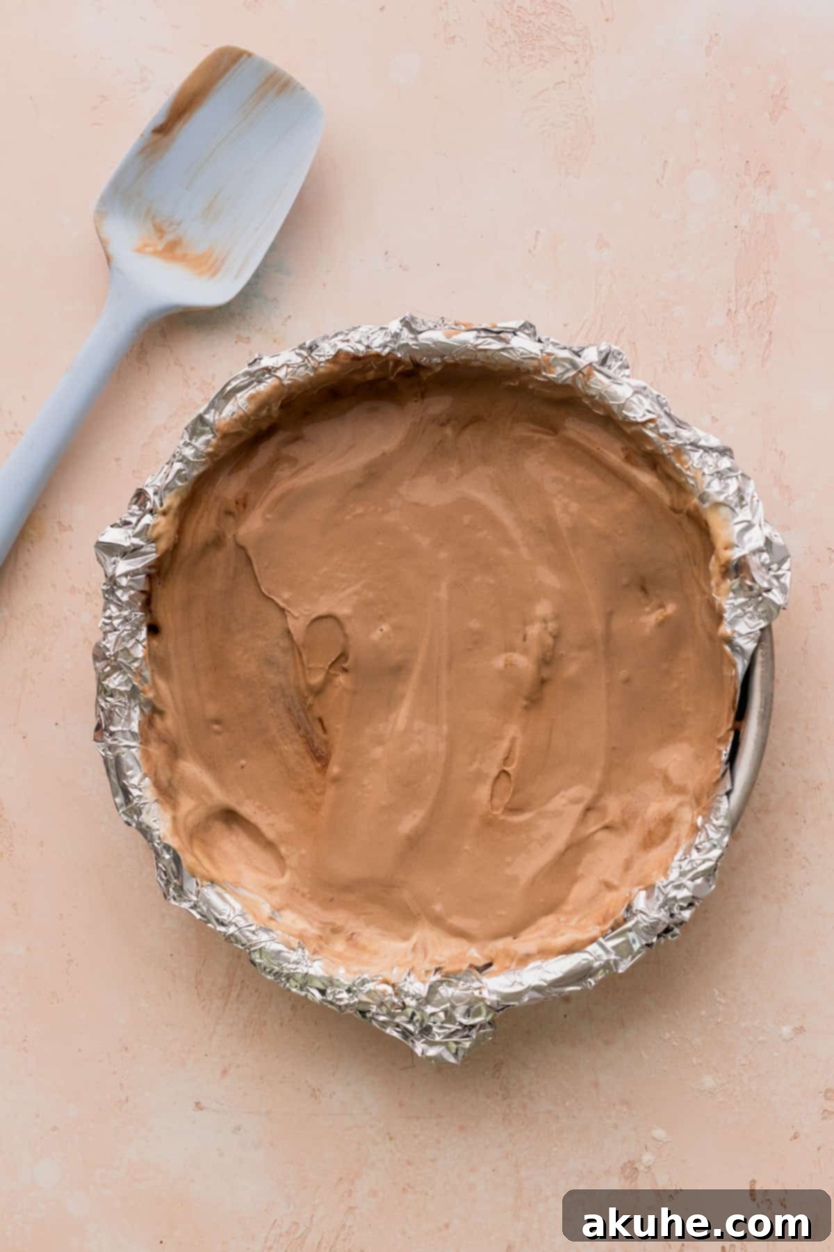 Ultimate Cookie Dough Ice Cream Cake 8 A layer of softened cookie dough ice cream evenly spread in a cake pan, ready for freezing.