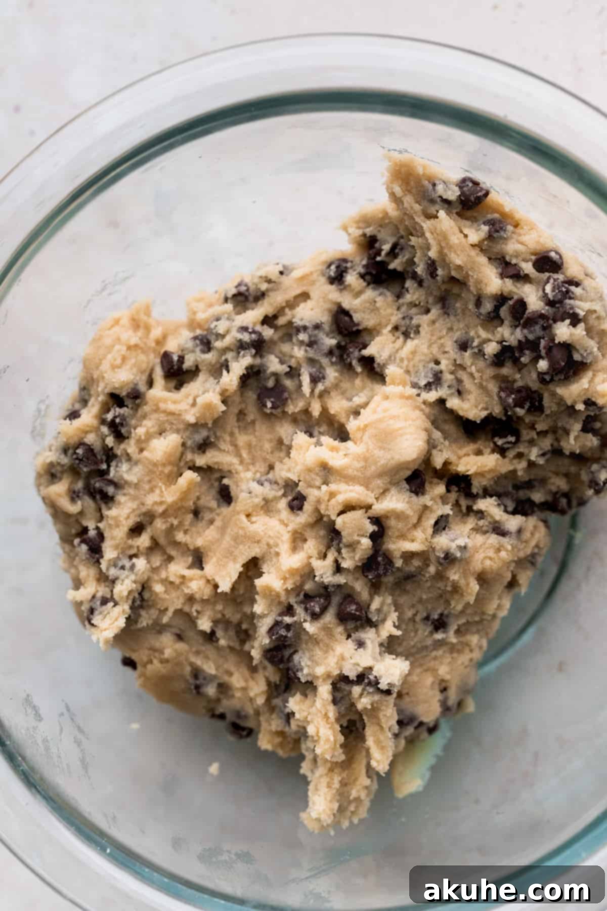 Ultimate Cookie Dough Ice Cream Cake 9 Homemade edible cookie dough, rich with chocolate chips, in a clear glass bowl.