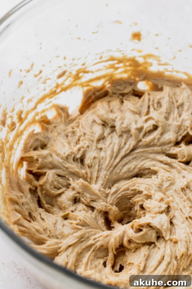 Gooey S'mores Cookies 4 A mixing bowl containing wet ingredients for s'mores cookies, including butter, brown butter, and sugars, before being beaten.