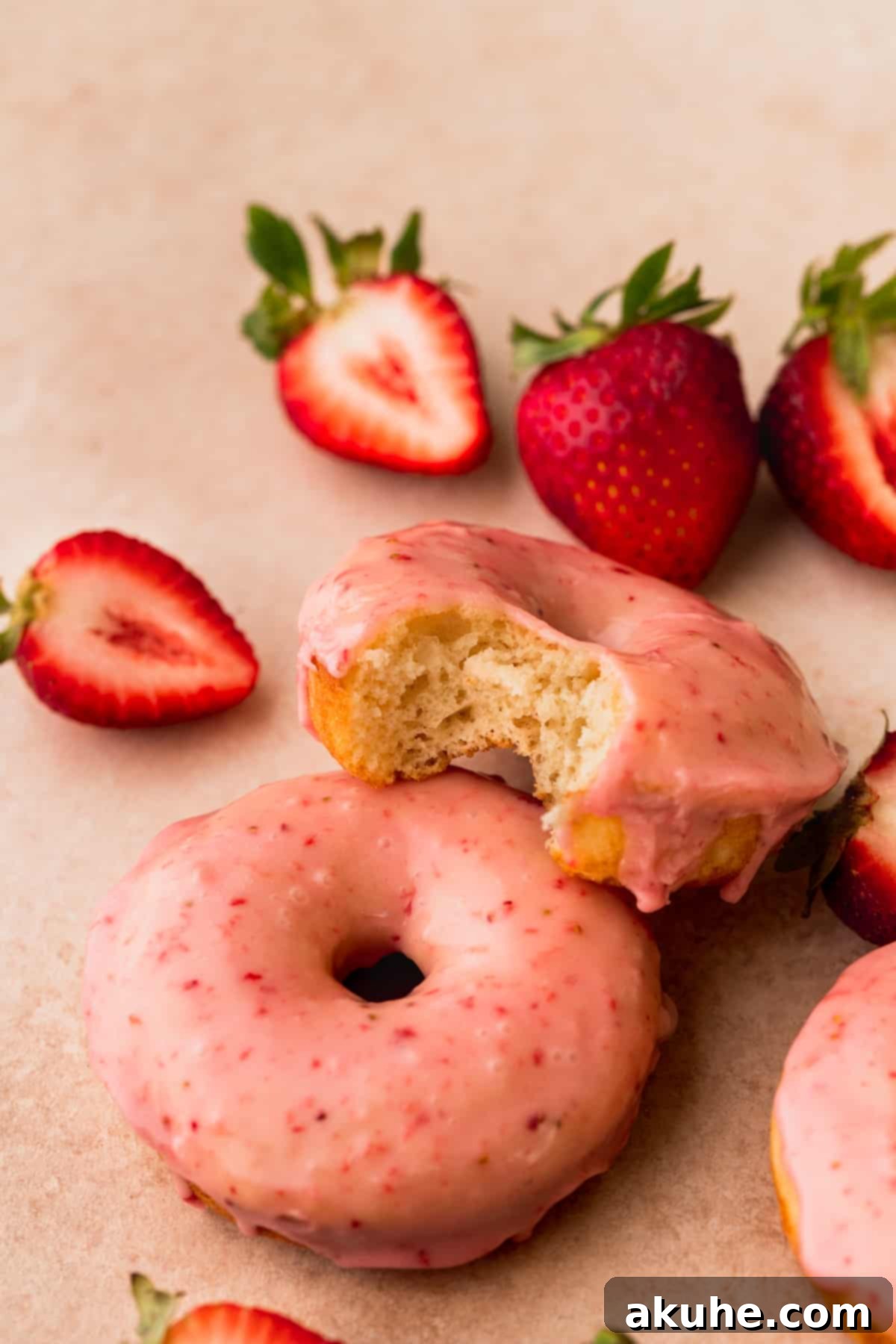 Glazed Strawberry Treats 11 Bite missing from donuts on top of another donut.