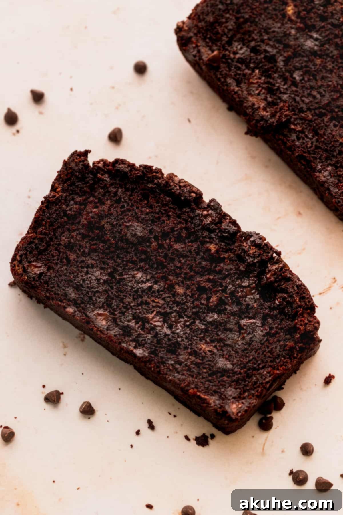 Decadent Double Chocolate Banana Bread 2 A perfectly baked slice of double chocolate banana bread, rich with chocolate chips, presented on a white surface.