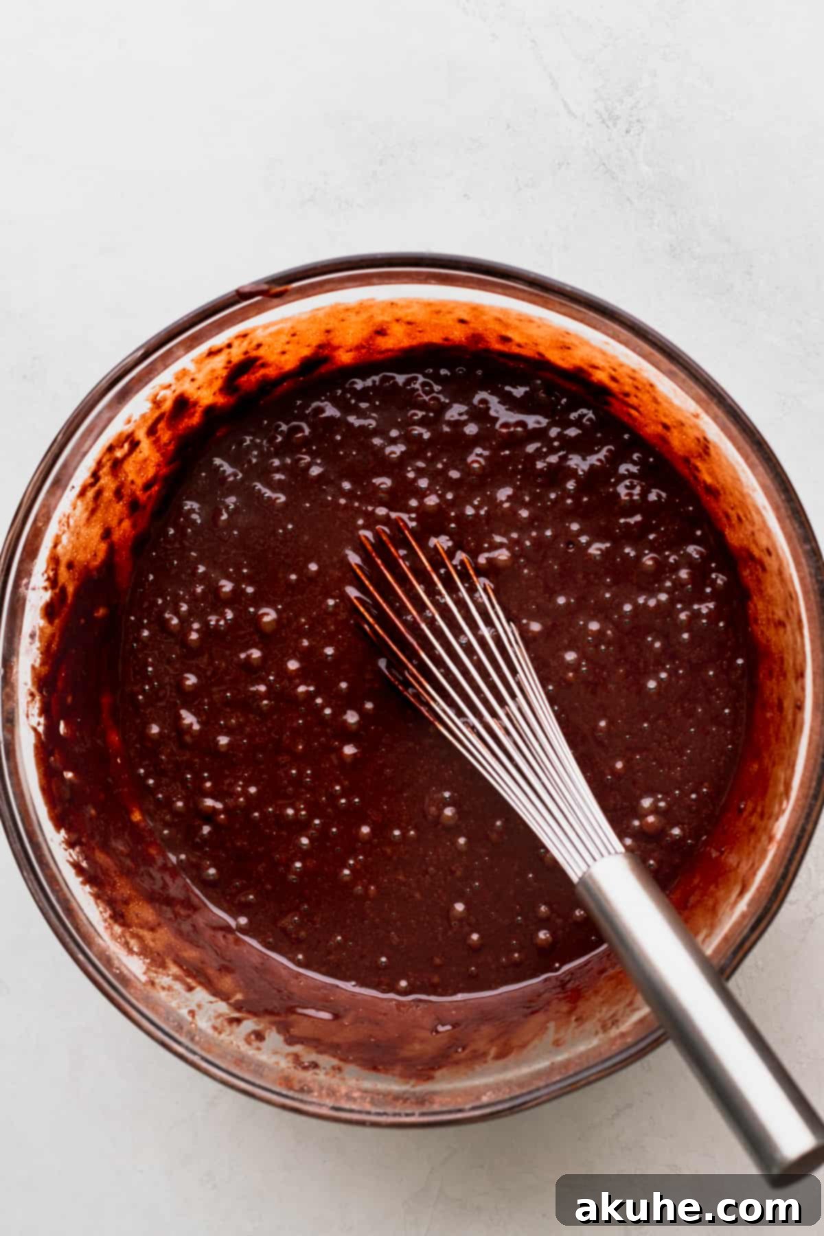 Chocolate cake batter in a glass bowl.