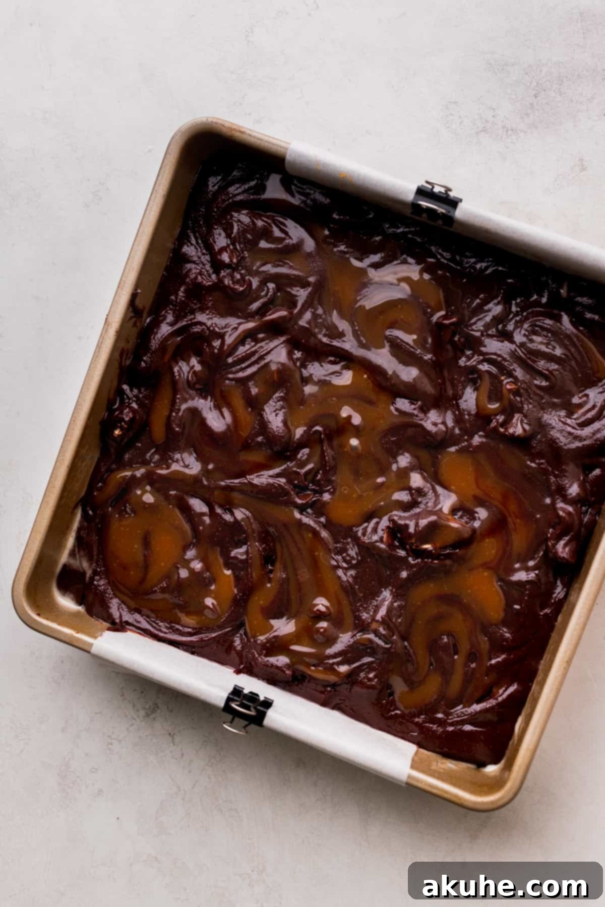 Snickers Brownies 8 Caramel on top of brownie batter in a pan.