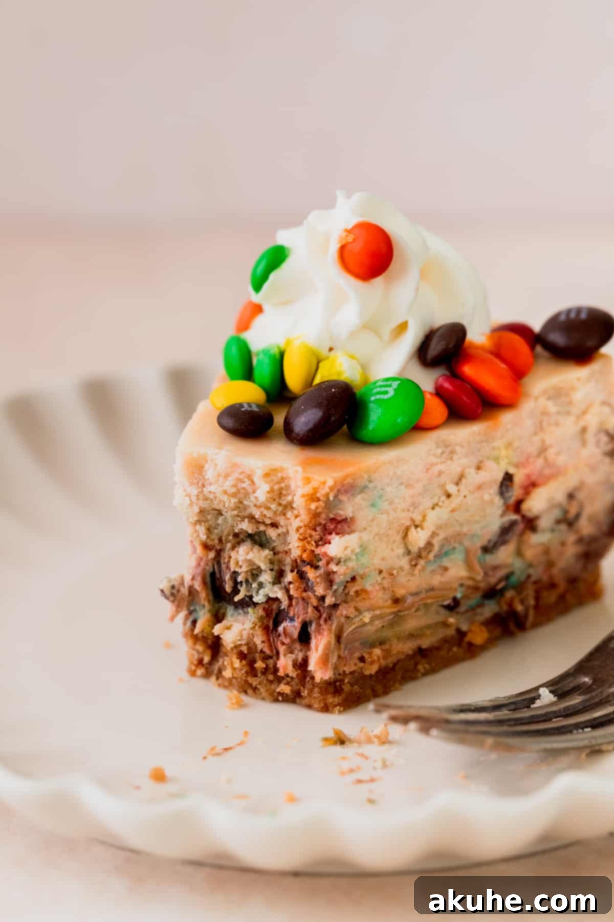 MM Cheesecake Bliss 11 A slice of M&M cheesecake with a bite missing, showcasing the creamy filling and crunchy crust.