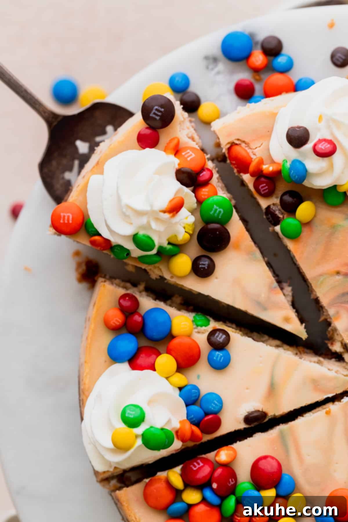 MM Cheesecake Bliss 3 A slice of M&M cheesecake being removed from the pan.