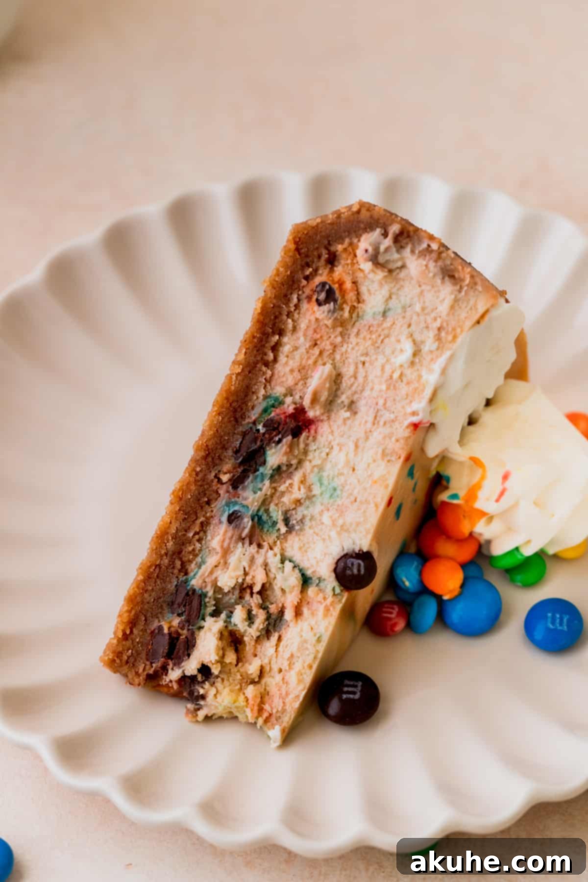 MM Cheesecake Bliss 10 One slice of M&M cheesecake on a plate, showing its creamy texture and colorful M&Ms.