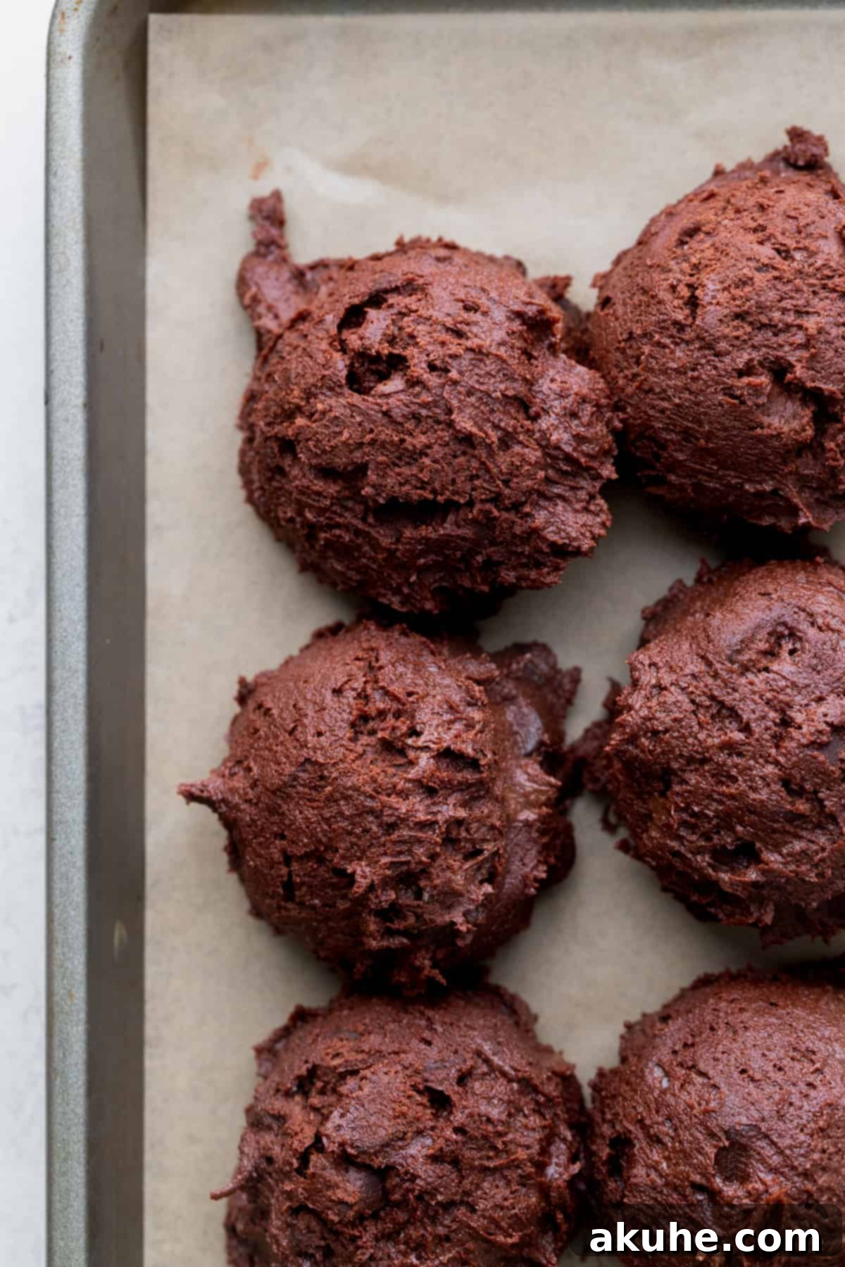 Ultimate Fudgy Crinkle Cookies 7 Cookie dough balls neatly arranged on parchment paper, ready to bake.