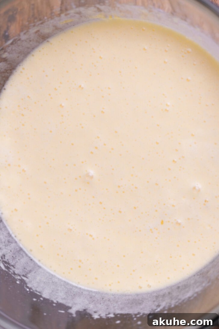 Wet ingredients (eggs and sugars) being beaten in a bowl until light and fluffy.