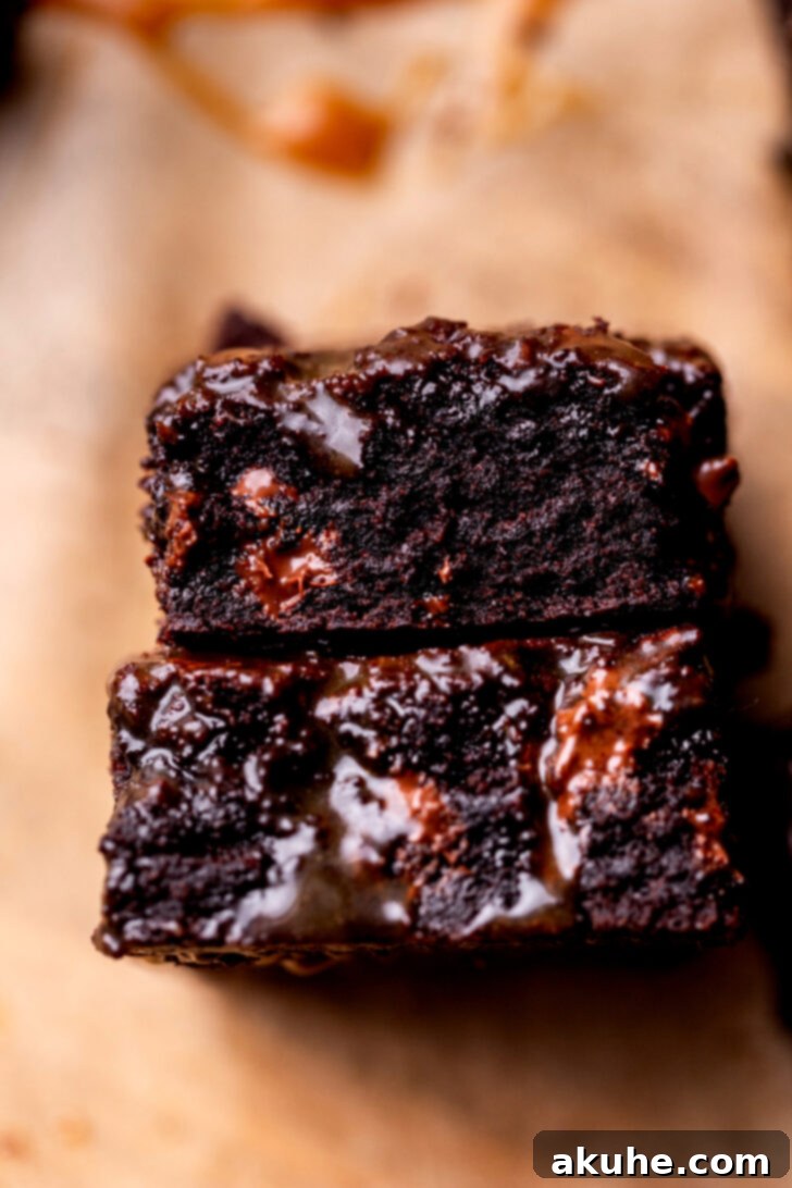 A stack of two perfectly cut salted caramel brownies, with visible caramel layers and a fudgy interior.