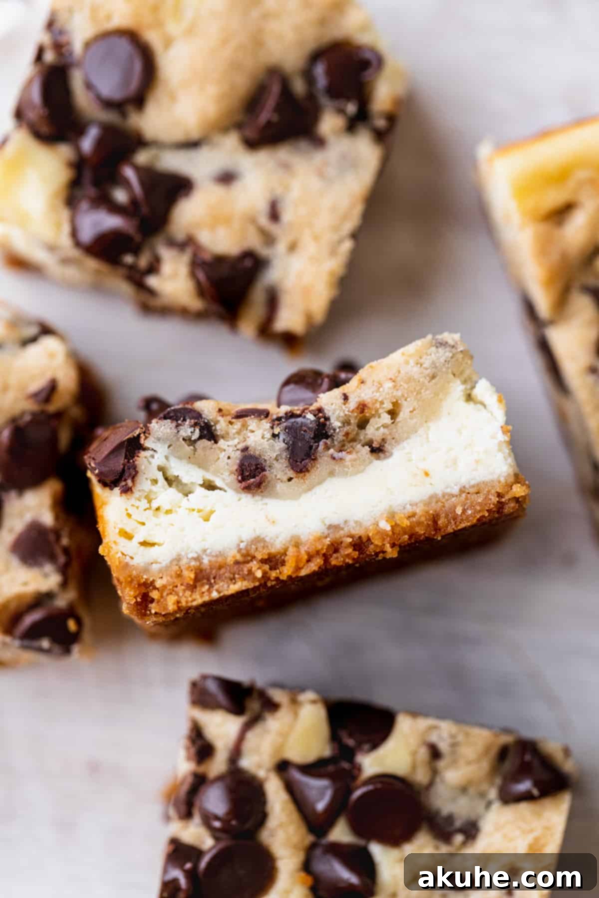 Decadent Cookie Dough Cheesecake Bars 11 Side view of a single Cookie Dough Cheesecake Bar on parchment paper, perfectly cut and highlighting its decadent layers.
