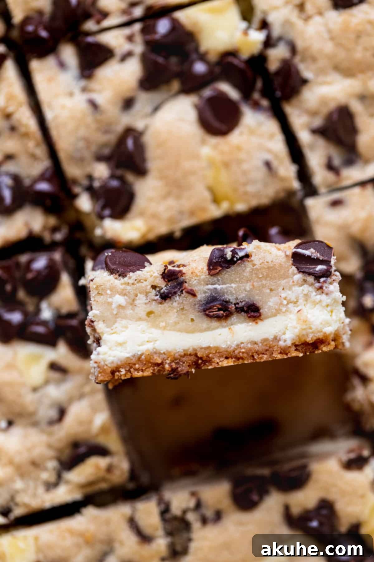 Decadent Cookie Dough Cheesecake Bars 3 Close-up side view of a Cookie Dough Cheesecake Bar, showing the distinct crust, creamy cheesecake, and gooey cookie dough layers.