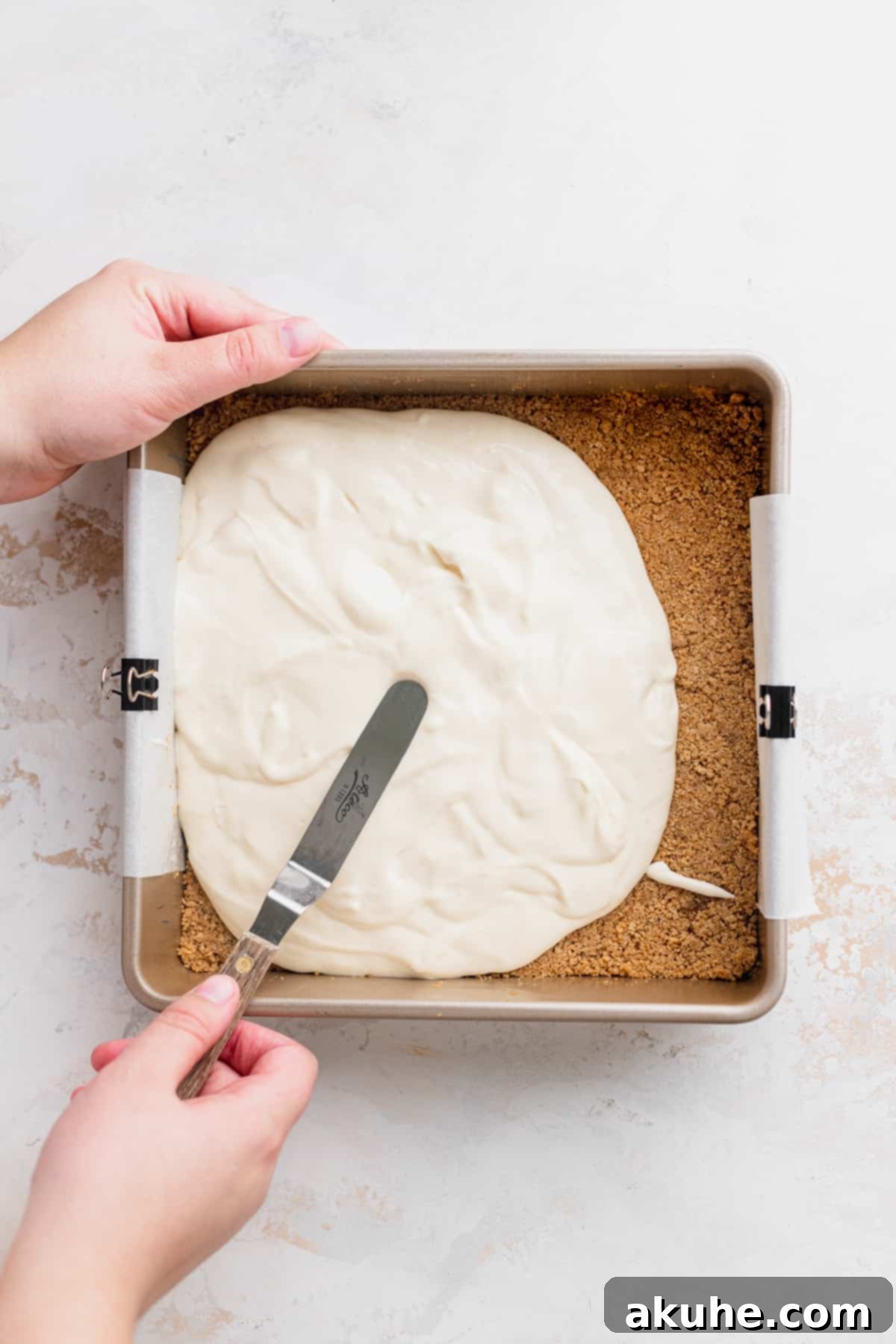 Decadent Cookie Dough Cheesecake Bars 7 Spreading smooth, white cheesecake batter evenly on top of the golden baked graham cracker crust.