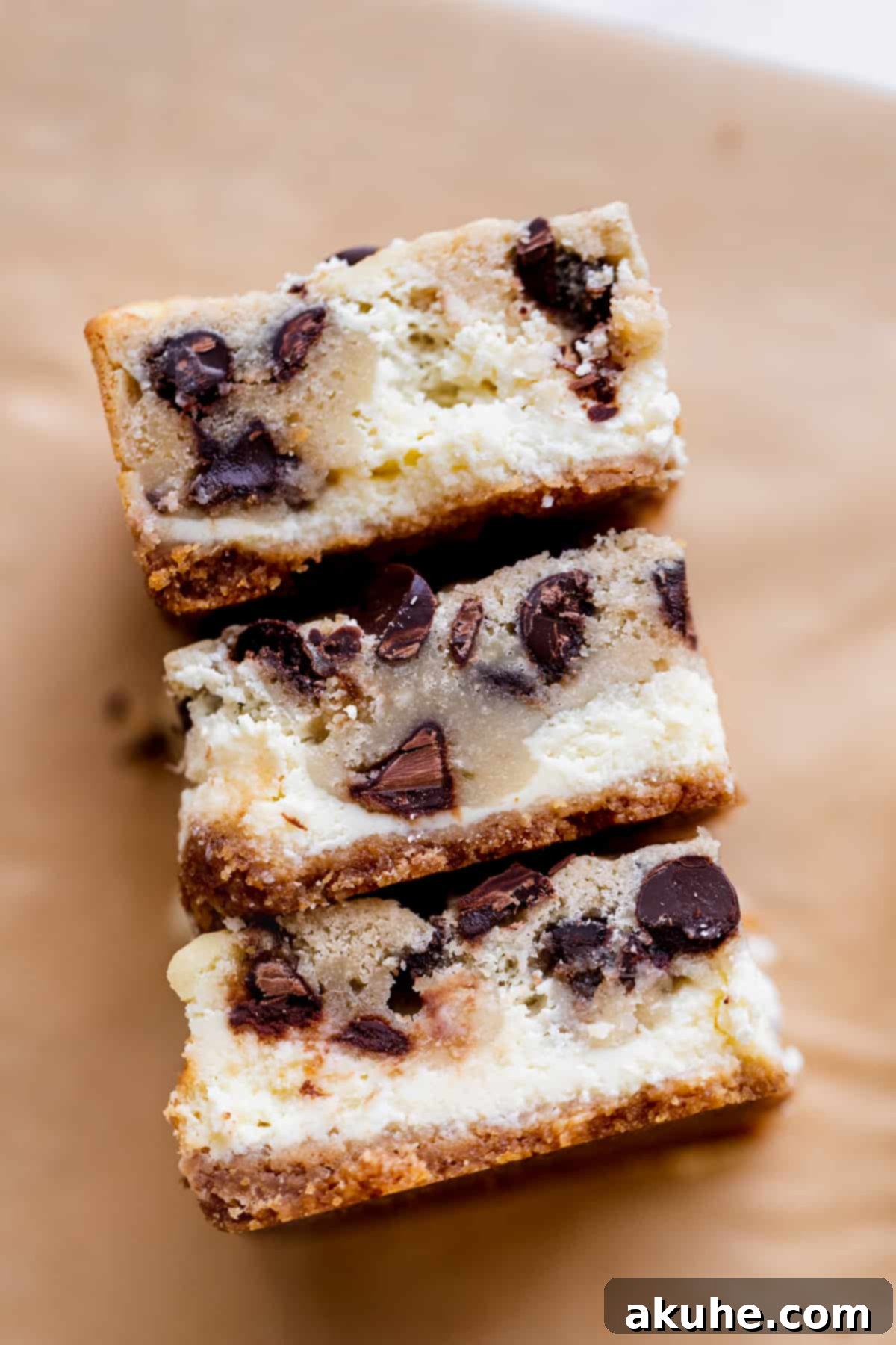 Decadent Cookie Dough Cheesecake Bars 9 Three perfectly cut and chilled Cookie Dough Cheesecake Bars standing on their sides on parchment paper, ready to be served.
