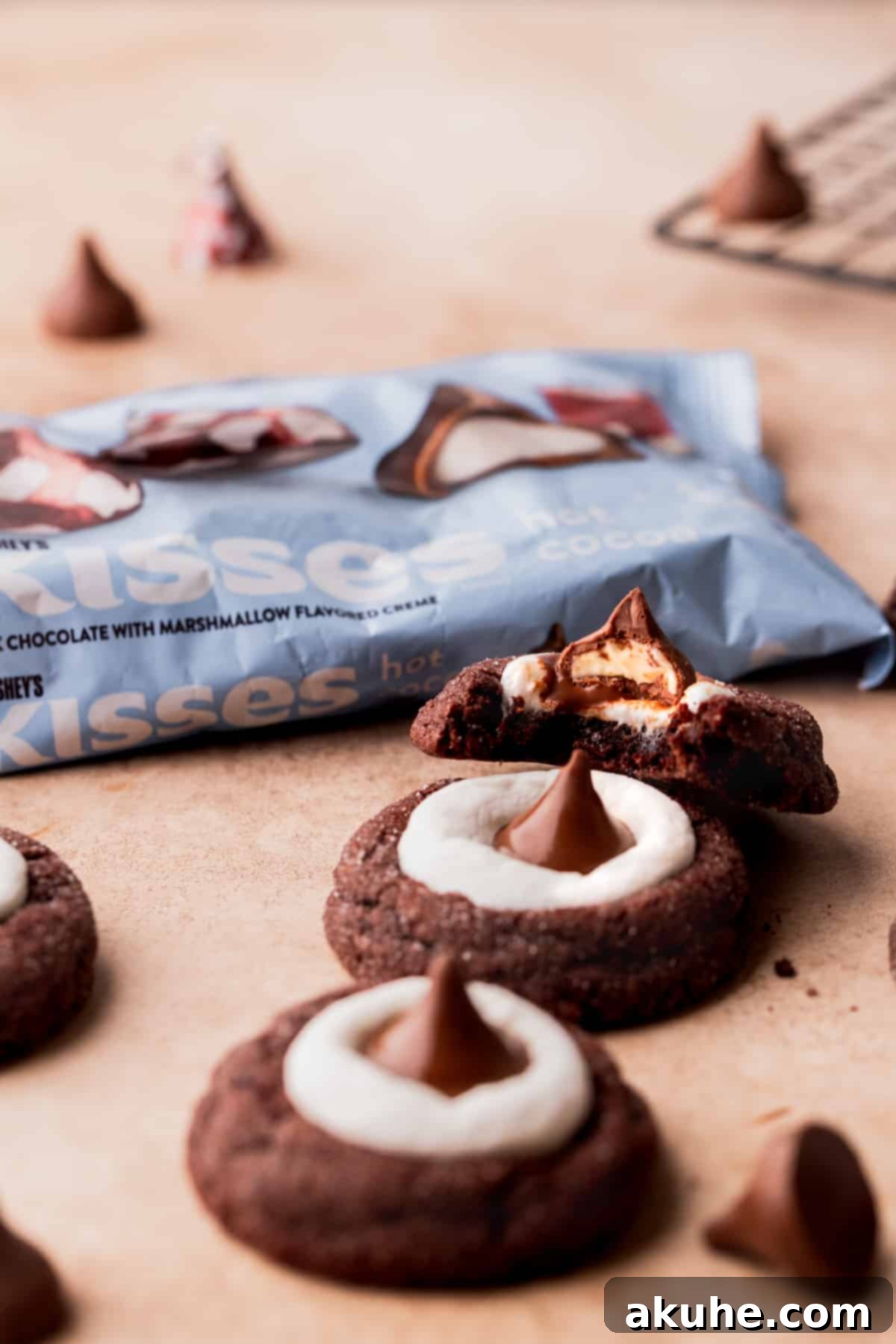Warm Cocoa Blossom Cookies 3 Close-up of a Hot Cocoa Cookie Blossom with a bite taken out, showing the fudgy texture and melted marshmallow, with a bag of Hershey's Hot Cocoa Kisses blurred in the background.