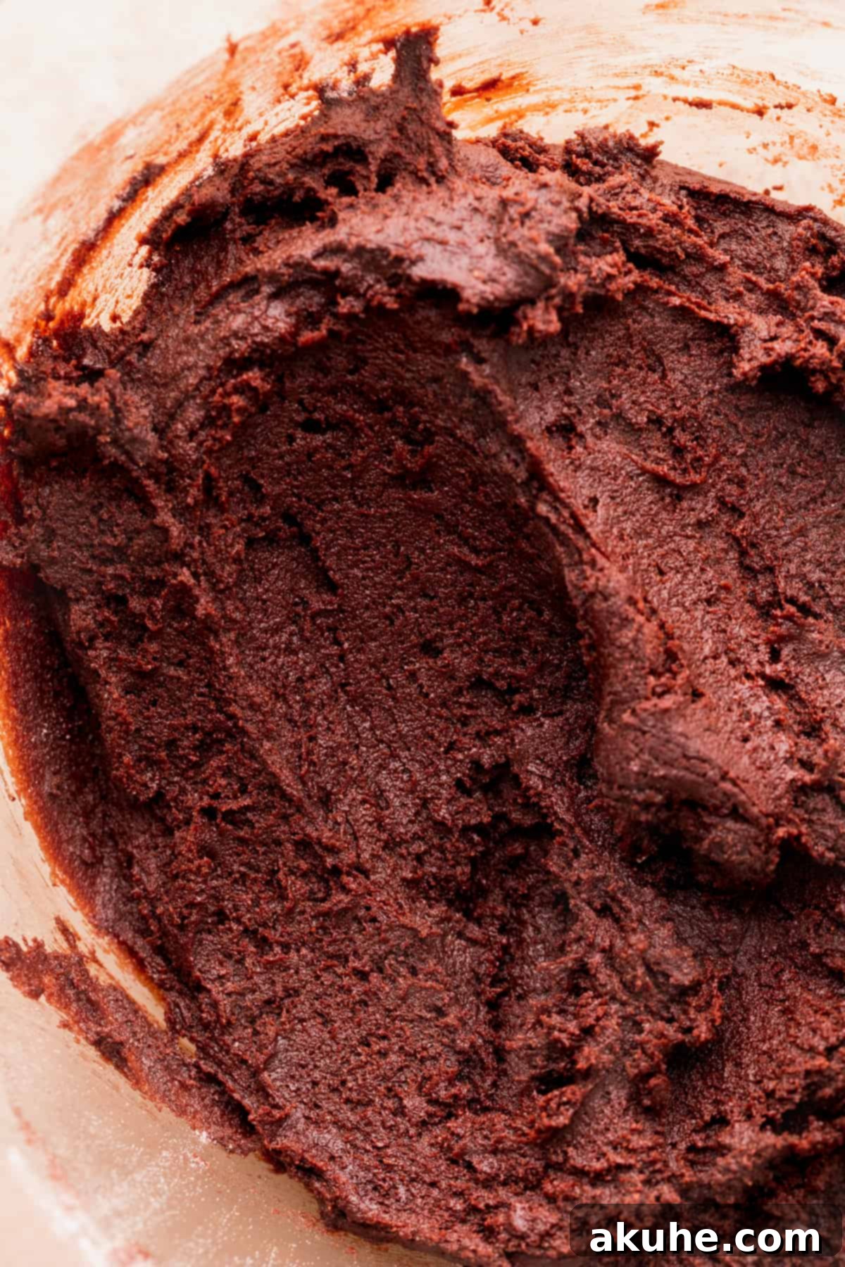 Warm Cocoa Blossom Cookies 5 Finished cookie dough in a glass bowl, showcasing its rich dark brown color and thick texture, ready for scooping.