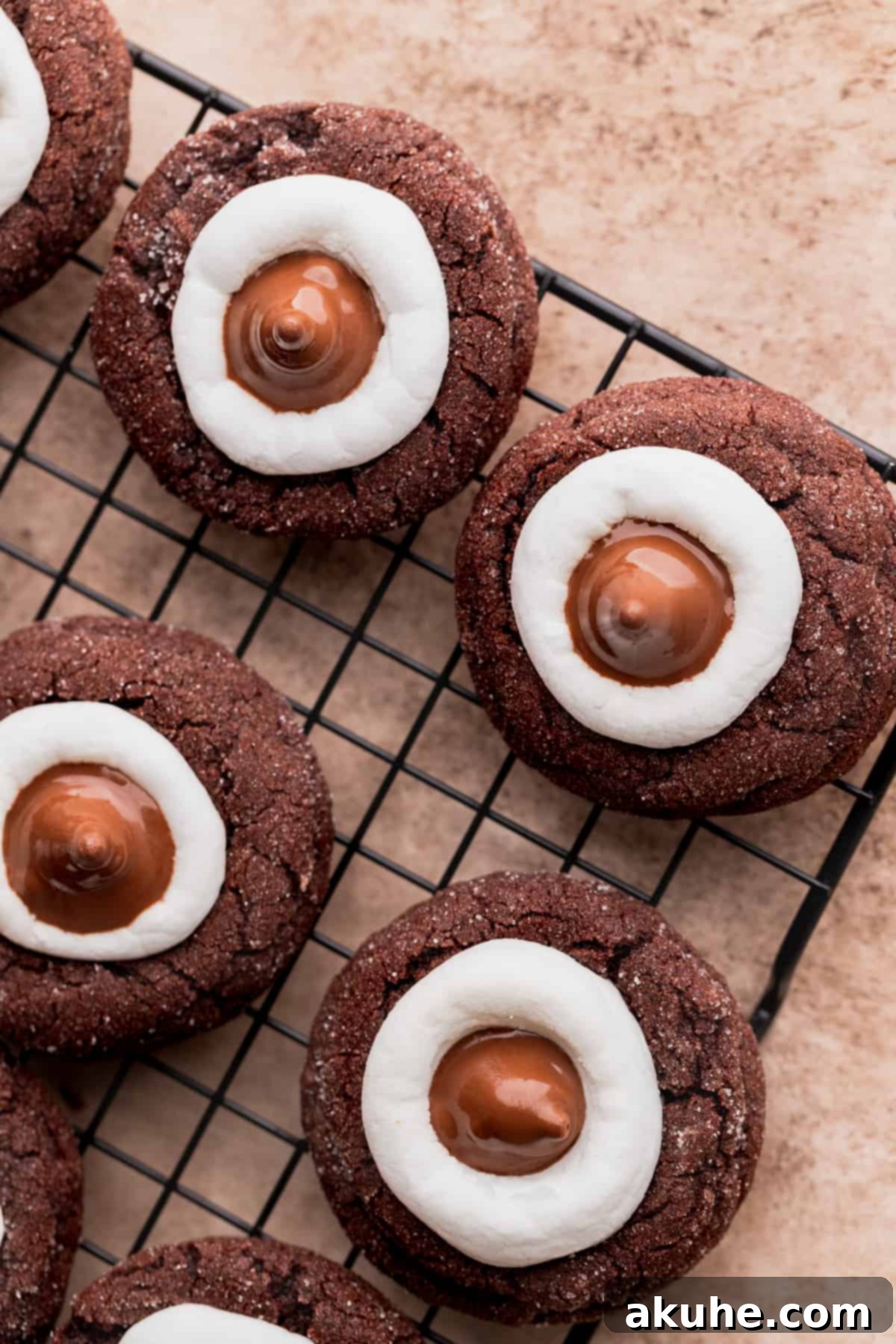 Warm Cocoa Blossom Cookies 9 A close-up view of Hot Cocoa Cookie Blossoms on a wire rack, each topped with a delicate Hershey's Hot Cocoa Kiss, showcasing the melted marshmallow base.