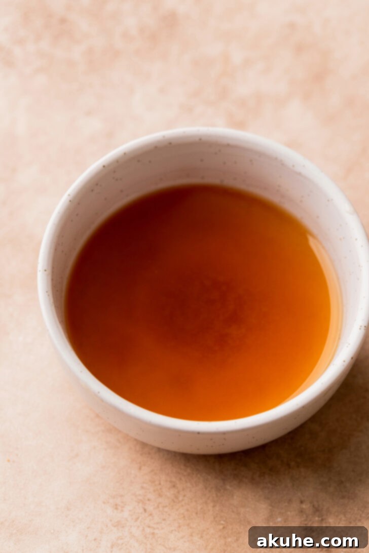 A bowl of rich, amber-colored reduced apple cider, ready for baking.