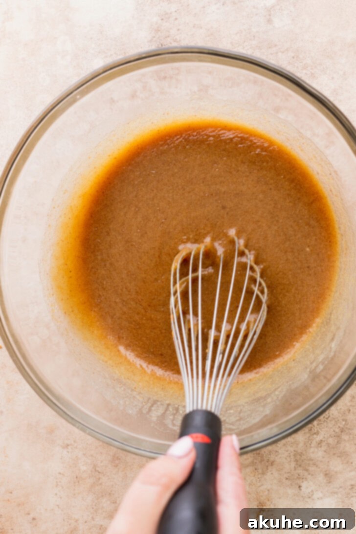 A bowl filled with wet ingredients, including brown butter and apple cider, ready to be mixed.