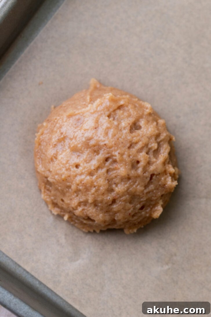Perfectly scooped cookie dough balls arranged on a parchment-lined cookie sheet.