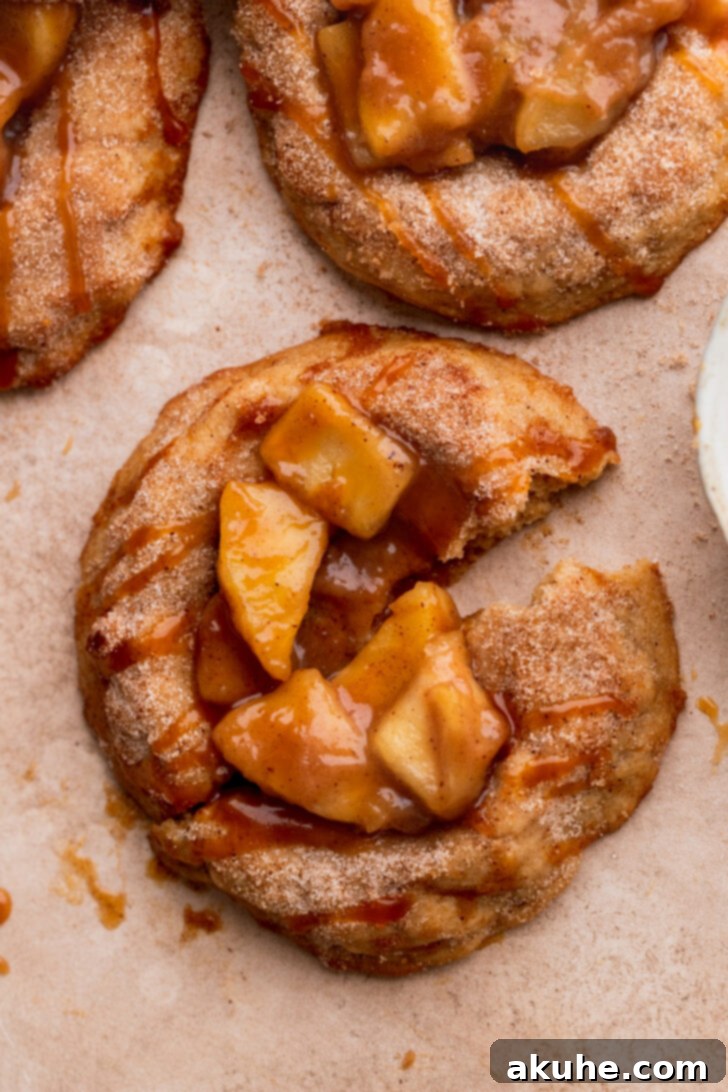 Spiced Apple Pie Cookies 2 One apple pie cookie split in half, revealing the soft cinnamon cookie, apple pie filling, and caramel drizzle.